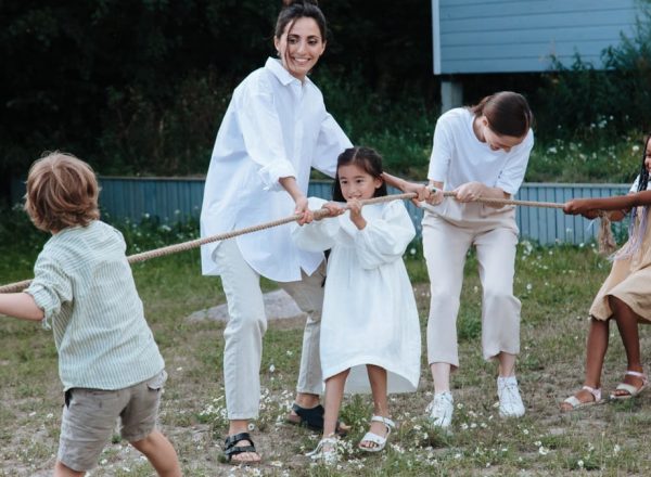 Family playing tug of war in backyard, showcasing teamwork and joy.