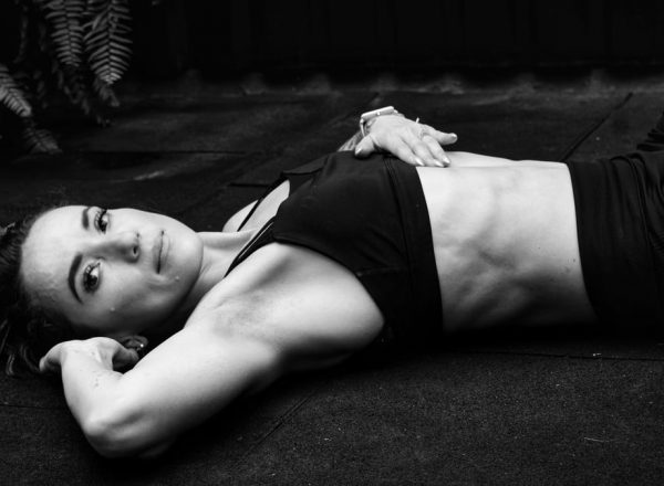 A woman in a sports bra lying on the floor in a contemplative pose.